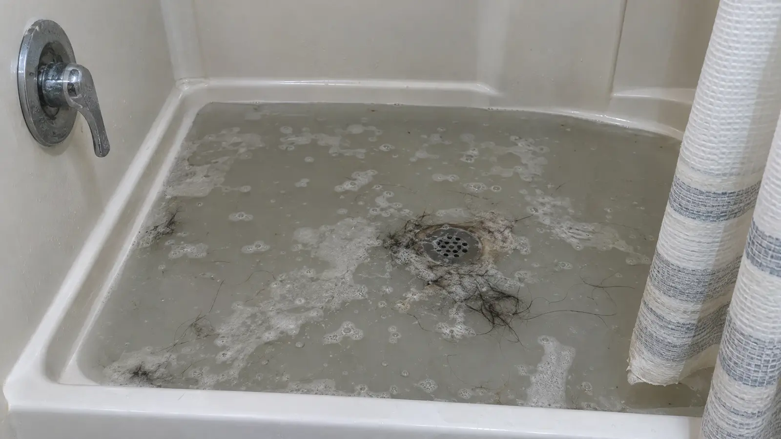 Before: a shower with standing soapy water and hair